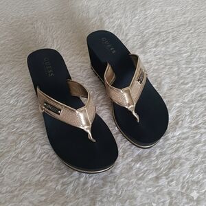 GUESS women's wedge sandals in gold with a black sole.